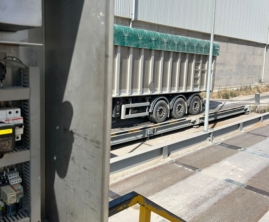 Camión granelero sobre una báscula de pesaje de camiones junto al armario de control de la instalación